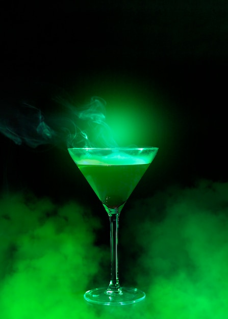 Free photo wineglass with liquor and green smoke