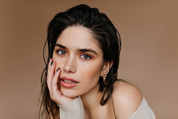 Winsome beautiful young woman posing on brown wall. Close-up shot of wonderful brunette girl.