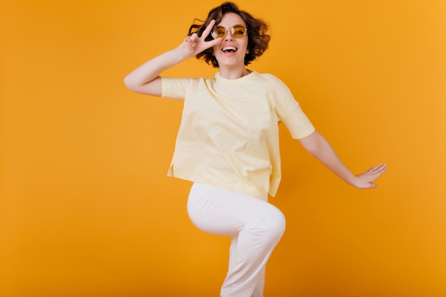 Free photo winsome short-haired girl in white attire dancing on orange space