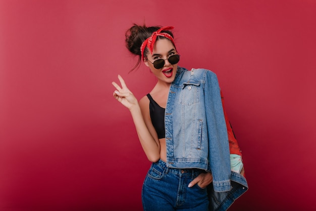 Winsome trendy lady in stylish sunglasses having fun during indoor photoshoot