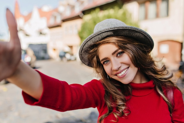 Free photo winsome white woman in knitted sweater making selfie while walking on avenue