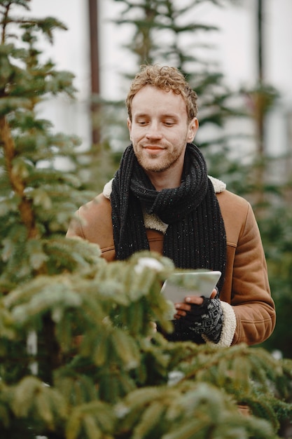 Free photo winter concept. guy in a brown coat. salesman of christmas tree.