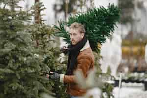 Free photo winter concept. guy in a brown coat. salesman of christmas tree.