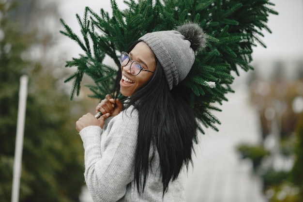 Winter concept. Woman in a gray sweater. Saleswoman of Christmas Tree.