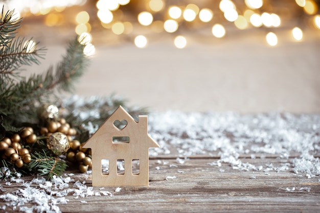 Winter cozy background with festive decor details, snow on a wooden table and bokeh. The concept of a festive atmosphere at home.