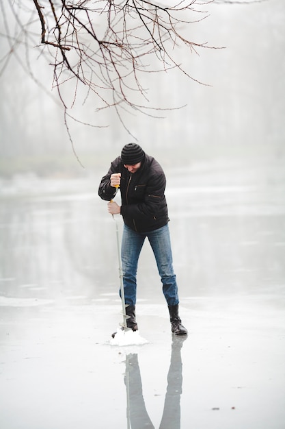 Winter fishing on the frozen lake with hand drill