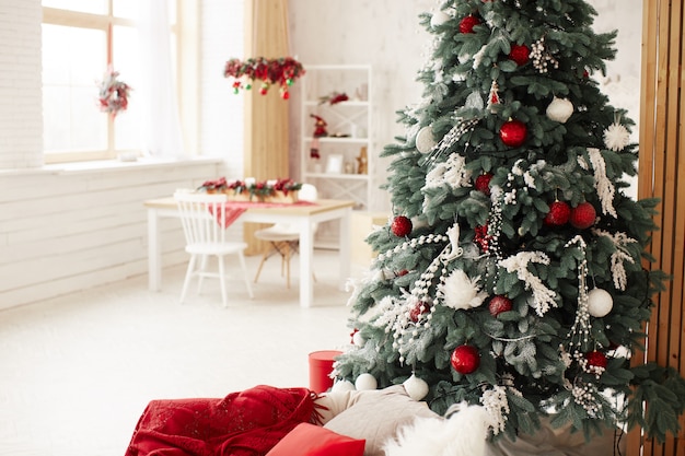 Winter holidays decor. Rich decorated New Year tree stands with present boxes