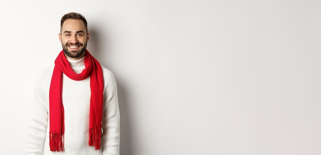 Free Photo winter holidays handsome adult man with red scarf looking happy at camera standing in sweater agains