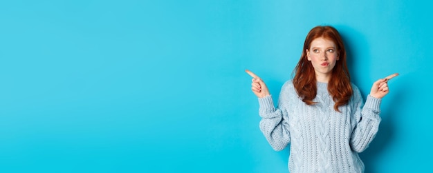 Free photo winter holidays and people concept thoughtful redhead girl making decision pointing fingers sideways