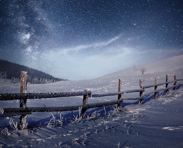 Free Photo winter landscape. mountain village in the ukrainian carpathians. vibrant night sky with stars and nebula and galaxy. deep sky astrophoto