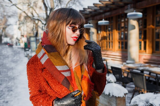 Winter portrait of elegant brunette woman in retro glasses posing outdoor