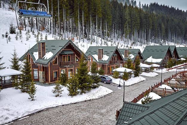 Free Photo winter vacation holiday wooden house in the mountains covered with snow and blue sky. skis in front of the house.