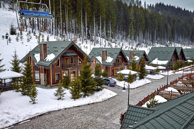 Winter vacation holiday wooden house in the mountains covered with snow and blue sky. Skis in front of the house.