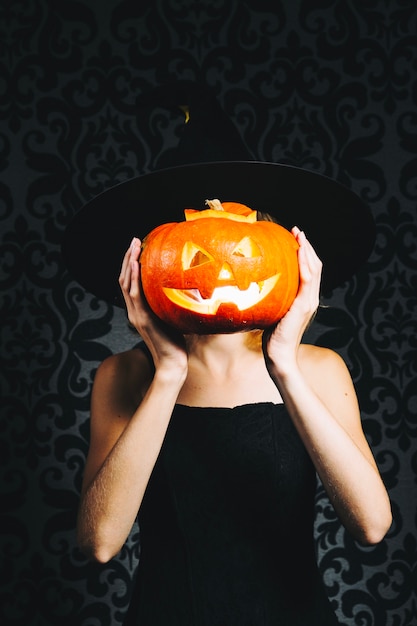 Free Photo witch covering face by pumpkin