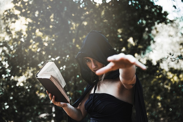 Free photo witch with spellbook using magic in sunlit woods