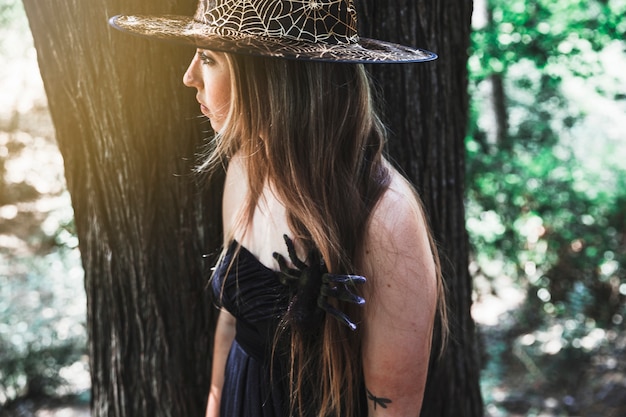 Witch with spider on chest in forest daytime