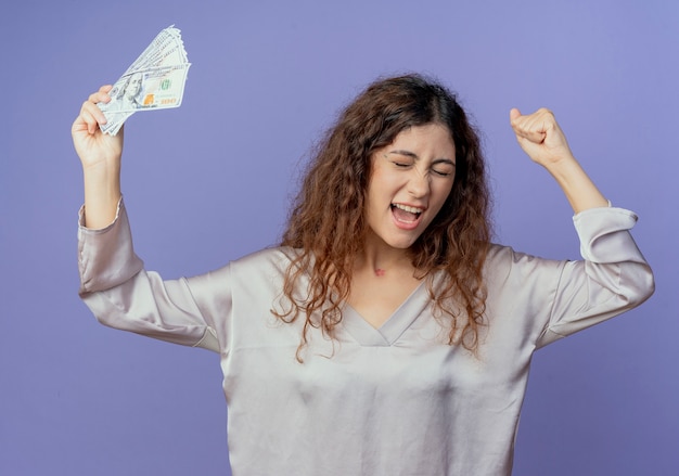 Free photo with closed eyes joyful young pretty girl raising hand and cash isolated on blue wall