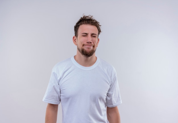 With closed eyes sorry young guy wearing white t-shirt on isolated white wall