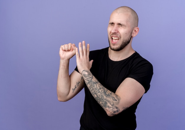 Free photo with closed eyes unpleased young sporty man showing different gestures isolated on purple