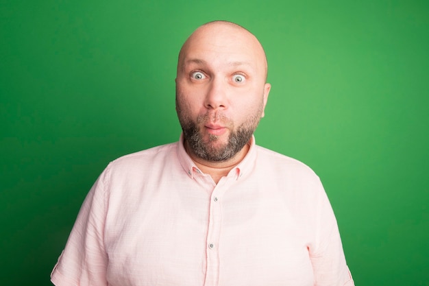 Free photo with puffed cheeks middle-aged bald man wearing pink t-shirt