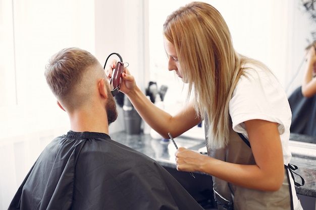 Woma shaving man's beard in a barbershop