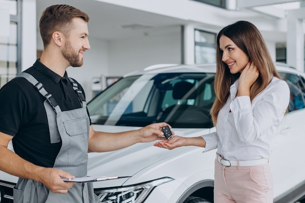 Woman at acr service station checking her car with mechanic