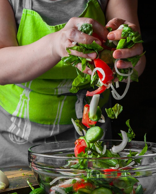 Woman adding vegetables into seasonal salad side view