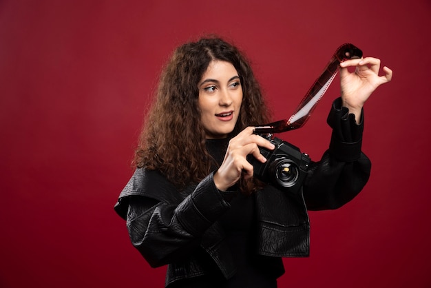 Woman in all black outfit holding a photo tape with a camera.