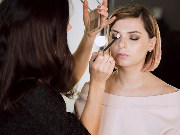 Woman applying cosmetics on model