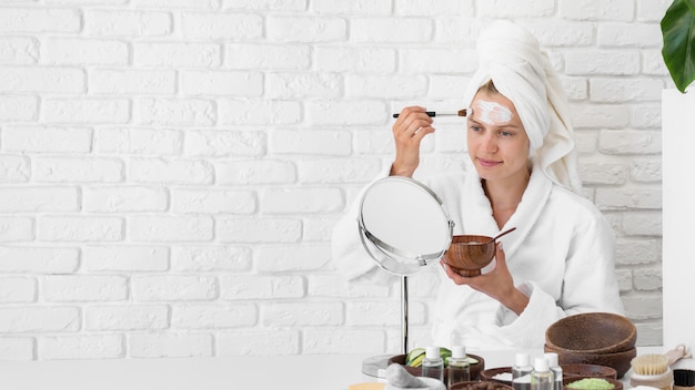 Free photo woman applying face remedy at home