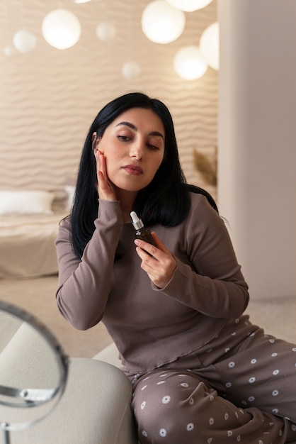 Free photo woman applying face serum during her beauty routine