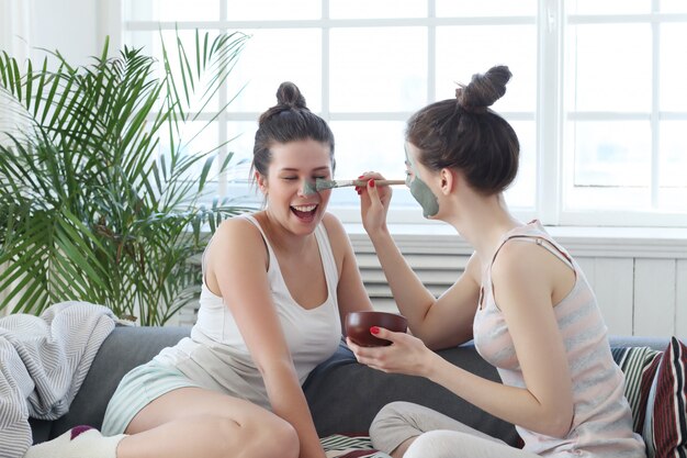 Woman applying a facial mask to her friend