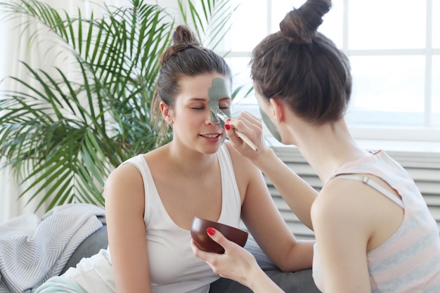 Woman applying a facial mask to her friend