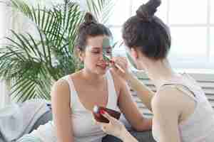 Free photo woman applying a facial mask to her friend