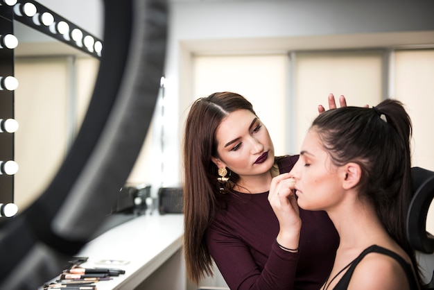 Free photo woman applying make up on model