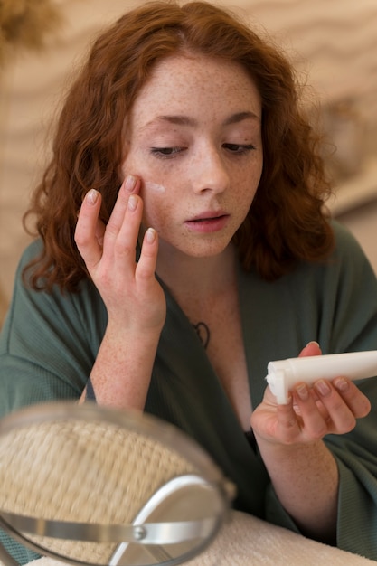 Free Photo woman applying moisturizer during her beauty routine