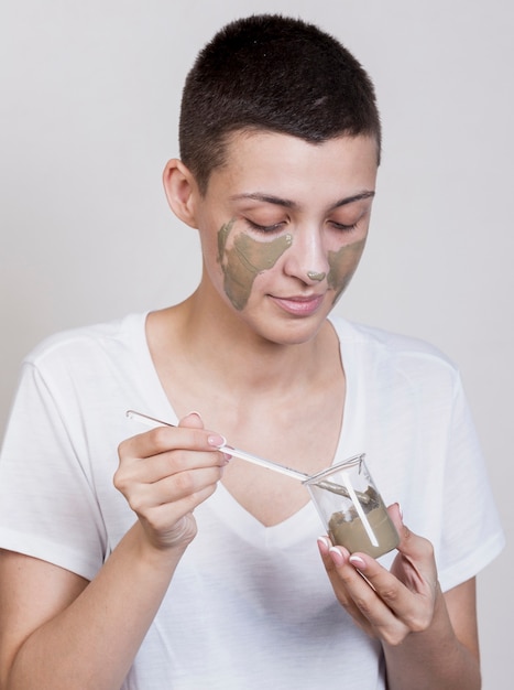 Free photo woman applying mud treatment on face