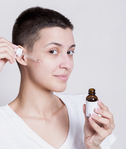 Woman applying serrum on face