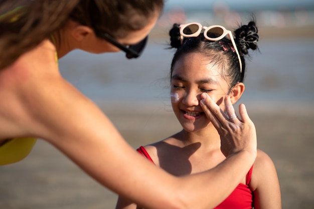 Woman applying sunscreen on kid front view