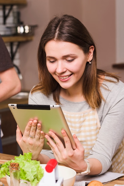 Woman in apron browsing tablet in kitchen 