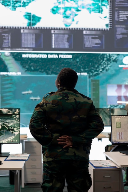 Free photo woman army conscript examines big screen with surveillance imagery