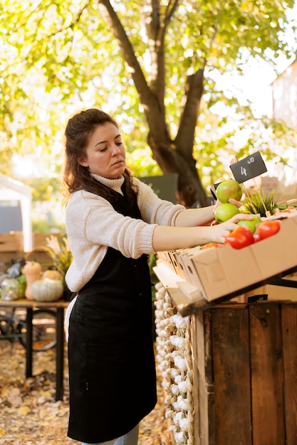 Free photo woman arranges fresh apples on booth