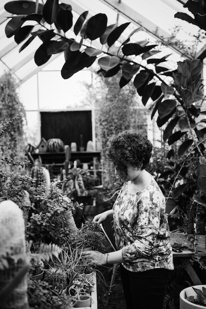 Free photo woman arranging flowers in a greenhouse