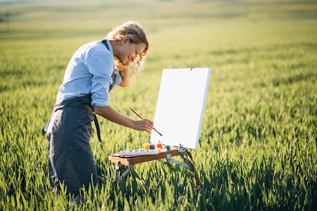 Free photo woman artist painting with oil paints in a field