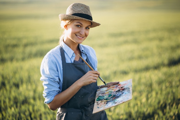 Woman artist painting with oil paints in a field