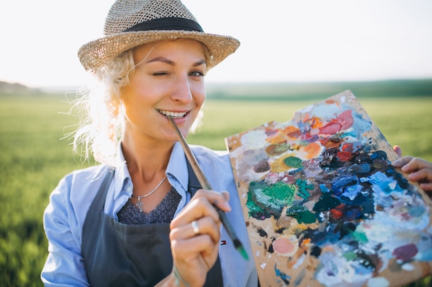 Free photo woman artist painting with oil paints in a field