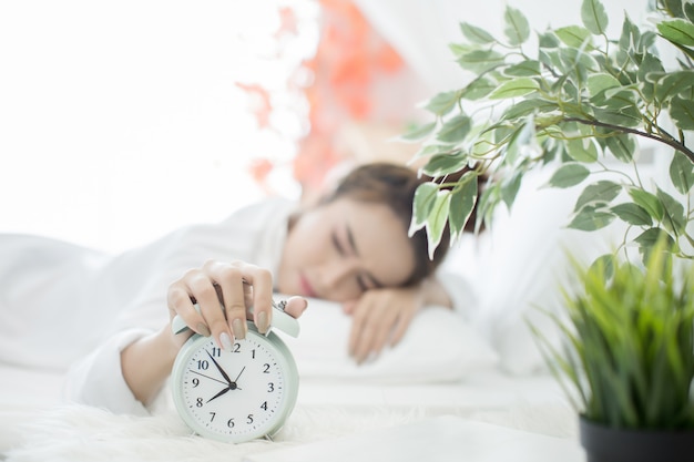 woman asleep in bed while her alarm shows the early time at home in bedroom