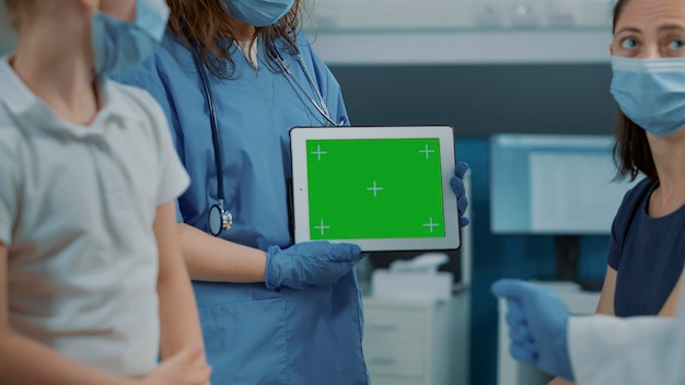 Free photo woman assistant holding horizontal green screen on tablet in office. medical nurse using isolated copy space template with chroma key mockup and blank background on gadget display at checkup.