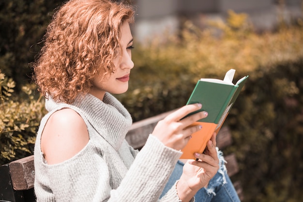 Free photo woman attentively reading book in park