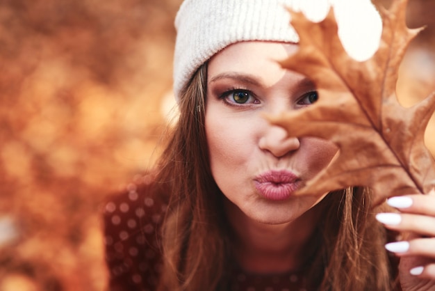 Woman in autumnal forest flowing a kiss